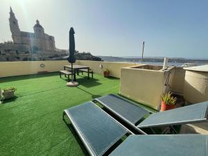 a balcony with green grass and a table and chairs at Unique Mellieha views, Sea Breeze in Mellieħa