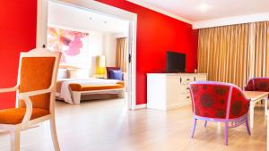 a bedroom with red walls and a bed and a mirror at Tongtara Riverview Hotel in Bangkok