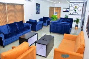 salon z niebieskimi kanapami i pomarańczowymi krzesłami w obiekcie Proxima Centauri Hotel w mieście Port Harcourt
