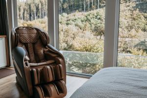 a bedroom with a chair in front of a window at Bungalow im Schwarzwald auf wunderschönem Anwesen in Neubulach