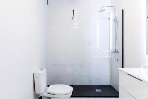 ein weißes Bad mit einem WC und einer Dusche in der Unterkunft Lovely 2-bedroom home in Pueblo Nuevo de Guadiaro in Guadiaro