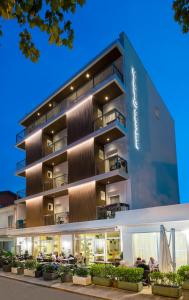 Un bâtiment avec des personnes assises à l'extérieur dans l'établissement Hotel Giulio Cesare, à Cattolica