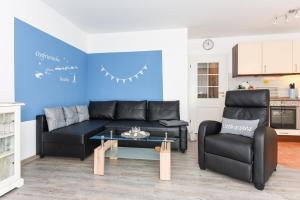sala de estar con sofá negro y 2 sillas en Ferienwohnung to Huus, en Bensersiel