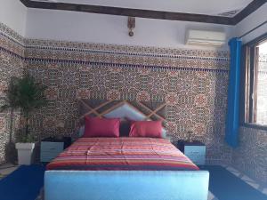 Schlafzimmer mit einem Bett und einer Wand mit Fliesen in der Unterkunft Appart Artisanal BATHA Fez in Fès