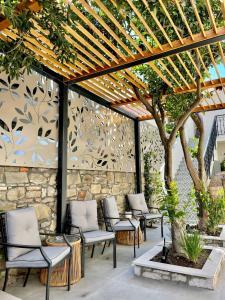 un patio con sillas bajo una pérgola de madera en Aesthesis Arxontiko Luxury Rooms, en Mirina