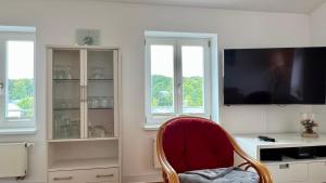 ein Wohnzimmer mit einem roten Stuhl und einem TV in der Unterkunft Villa Sonneck - Wohnung 21 in Ostseebad Sellin