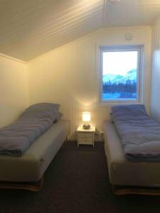 2 Betten in einem Zimmer mit Fenster in der Unterkunft Mountainside Lodge - Breivikeidet in Tromsø