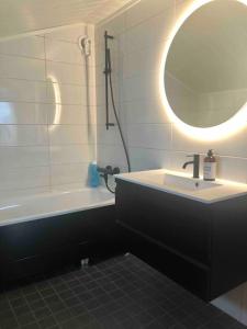 uma casa de banho com um lavatório, um espelho e uma banheira em Mountainside Lodge - Breivikeidet em Tromsø
