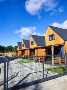 eine Häuserreihe mit einem Zaun davor in der Unterkunft Zielonka Relaks in Rusinowo