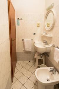 a bathroom with a sink and a toilet and a mirror at Hotel Zanella in Cervia