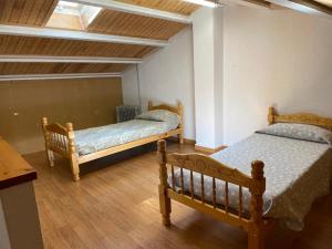two beds in a room with wooden floors at Cal Carbassó in Pardines