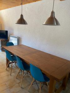 a large wooden table with blue chairs and lights at Cal Carbassó in Pardines