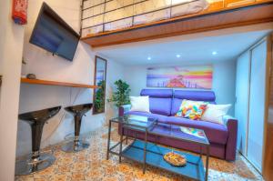 ein Wohnzimmer mit einem lila Sofa und einem Flachbild-TV in der Unterkunft Cozy & cute studio in the heart of Valletta GOVAL2 in Valletta