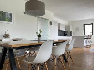 cocina y comedor con mesa de madera y sillas blancas en Ferienhaus Simon, en Wadern
