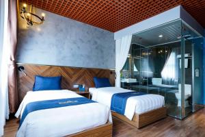 two beds in a room with a shower and a bathroom at 1925 Ha Long Hotel in Ha Long