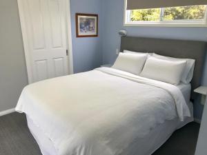 a white bed with white pillows and a window at Apple Tree Cottage - Comboyne Mountain Cottages in Comboyne