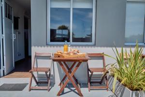 Riviera del Sur - Apart hotel في ميرامار: طاولة خشبية مع كرسيين وزجاجة من النبيذ