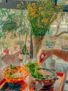 una mesa con un tazón de comida y un jarrón con flores en Hoa Thi hotel, en Tiên Tân