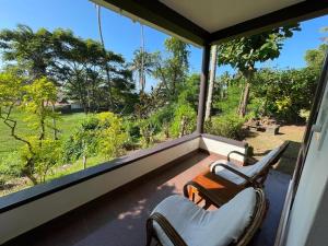 a screened in porch with two chairs and a large window at The First Place Yogaresort, Odayam in Varkala