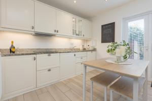 una cucina con armadi bianchi e tavolo in legno di Charles Alexander Short Stay - Rose Cottage a Lytham St Annes