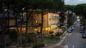 Blick auf eine Straße mit einem Gebäude und geparkten Autos in der Unterkunft Hotel Zanella in Cervia
