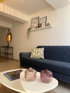 uma sala de estar com um sofá azul e uma mesa em Oasis de 42 m2 I Cosy I Cœur de ville I Lit 160x200 em Vaison-la-Romaine