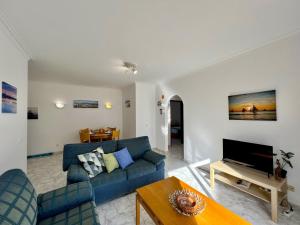 a living room with a blue couch and a table at Albufeira Falesia Beach 4 by Homing in Albufeira