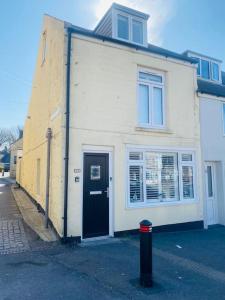 a white house with a black door on a street at Foundry Cottage in Portland