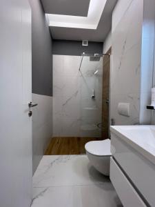 a white bathroom with a toilet and a shower at OLYMPIC 84 Apartments in Sarajevo