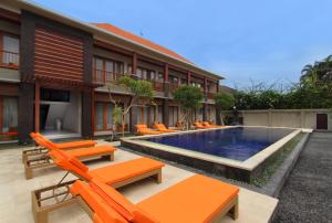 a resort with a swimming pool and orange lounge chairs at Kubu Cempaka Seminyak in Seminyak