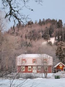 una casa roja en la nieve con una montaña en Villa Näs - a modern country villa en Mullsjö
