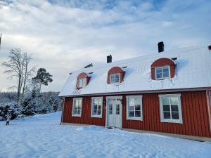 a red house with a white roof in the snow at Villa Näs - a modern country villa in Mullsjö