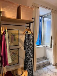 einen Schrank mit einem Kleid, einem Hut und einem Fenster in der Unterkunft casa turchina in Neapel