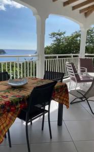 a table and chairs on a porch with the ocean at villa vue sur mer in Deshaies