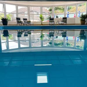 a pool with chairs and a table in a building at Sunset sea view chalet with hot tub in Torpoint