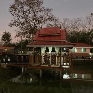 a house with a deck next to a body of water at Nantawanhomestay in Lampang