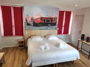 een slaapkamer met een bed en een schilderij van een rode auto bij Malicorn' Appart-Hôtel in Malicorne-sur-Sarthe