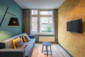 Una sala de estar con un sofá y un televisor en una pared. en Musea Hotel & Apartments, en Ámsterdam
