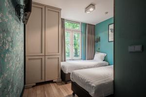 Una pequeña habitación con dos camas y una ventana. en Musea Hotel & Apartments, en Ámsterdam