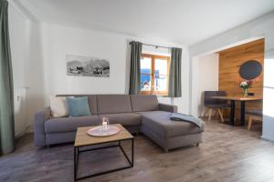 uma sala de estar com um sofá e uma mesa em Ferienwohnung Alpentraum - Wildblume em Fischen