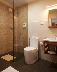 uma casa de banho com um WC, um chuveiro e um lavatório. em The Willows Hotel, Bhutan em Thimphu