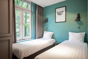 Dos camas en una habitación con paredes y ventanas azules. en Musea Hotel & Apartments, en Ámsterdam