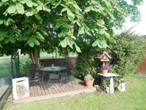 a wooden deck with a table and chairs under a tree at Ferienwohnung Kasch in Krummin