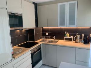 una cocina con armarios blancos y electrodomésticos de acero inoxidable en Roc d'Orsay C15 en Leysin