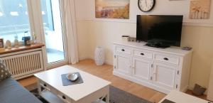 ein Wohnzimmer mit einem Flachbild-TV auf einem weißen Schrank in der Unterkunft Wohnung Alina in Westerland