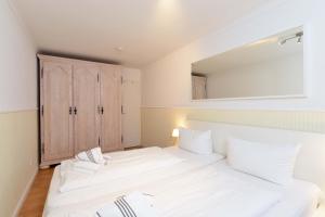 - une chambre avec un grand lit blanc et un miroir dans l'établissement Wohnung-Alina, à Westerland
