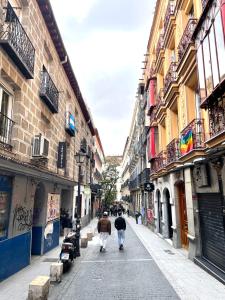 zwei Leute gehen eine Stadtstraße mit Gebäuden entlang in der Unterkunft Apartamento con encanto en el corazón de Chueca, Madrid in Madrid