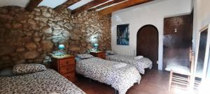 a bedroom with three beds and a stone wall at Cal Pau Cruset in Torrellas de Foix