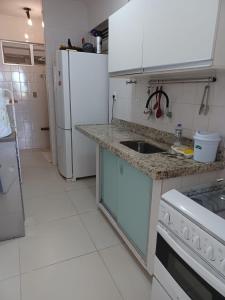 a white kitchen with a sink and a refrigerator at Apartamento em Camboinha in João Pessoa