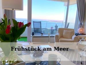 a living room with a couch and a table with flowers at Top - Seaside Appartement mit Meerblick in Timmendorfer Strand